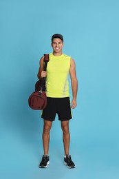 Handsome man with sports bag on light blue background