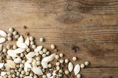 Mixed vegetable seeds on wooden background, flat lay. Space for text