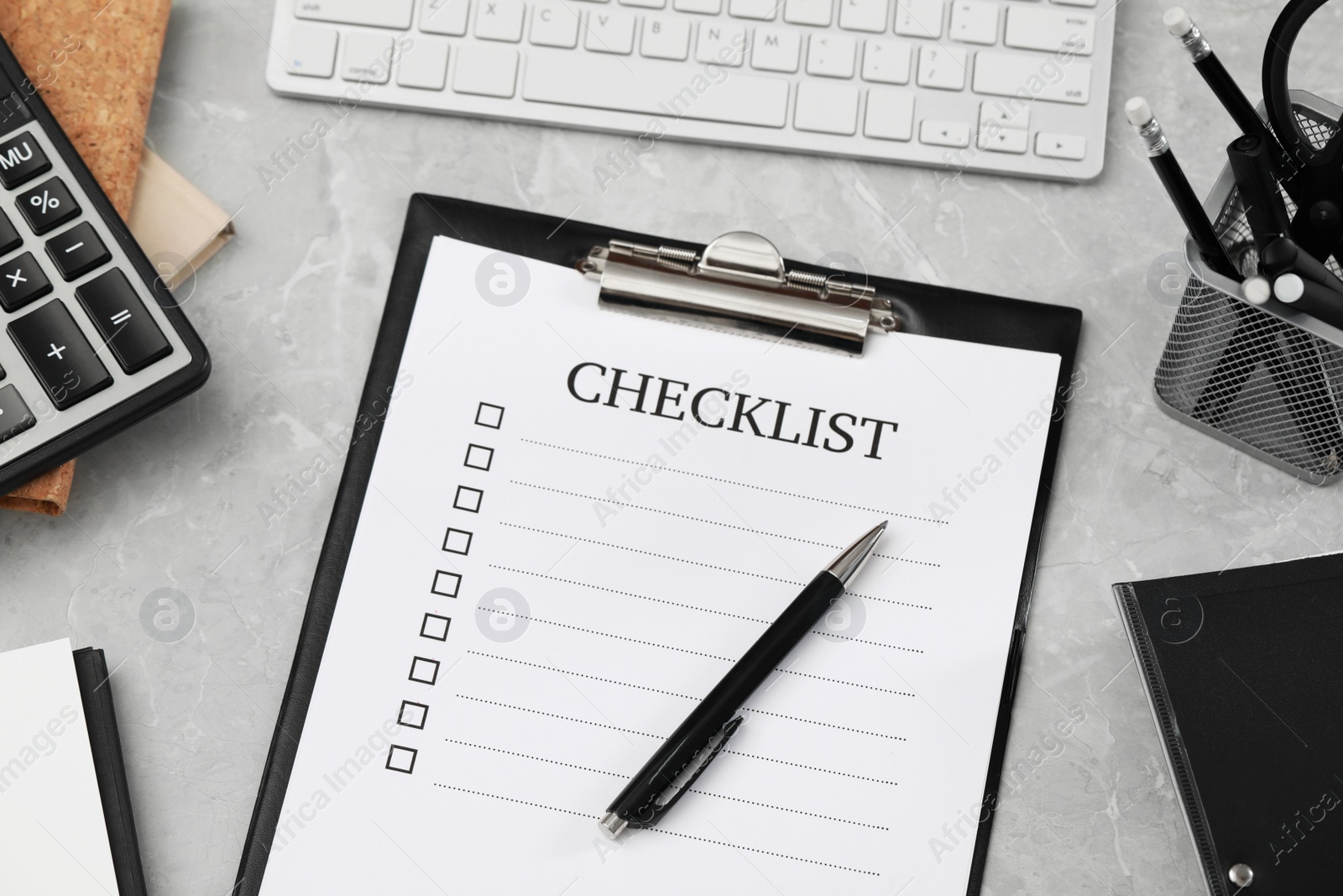 Photo of Clipboard with inscription Checklist and pen on grey marble table, above view