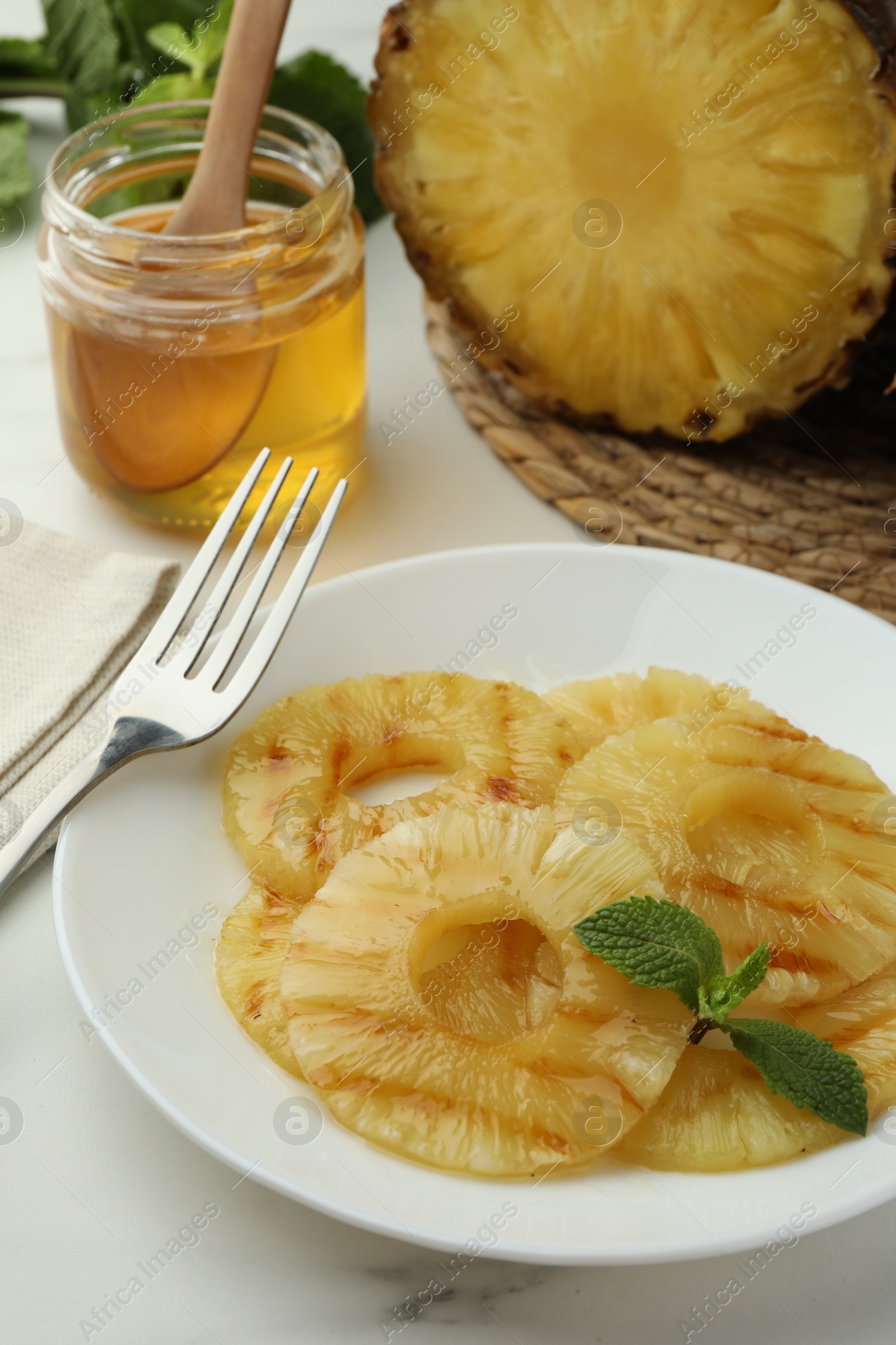 Photo of Tasty grilled pineapple slices served on white table