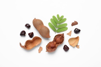 Photo of Delicious ripe tamarinds and leaves on white background, flat lay