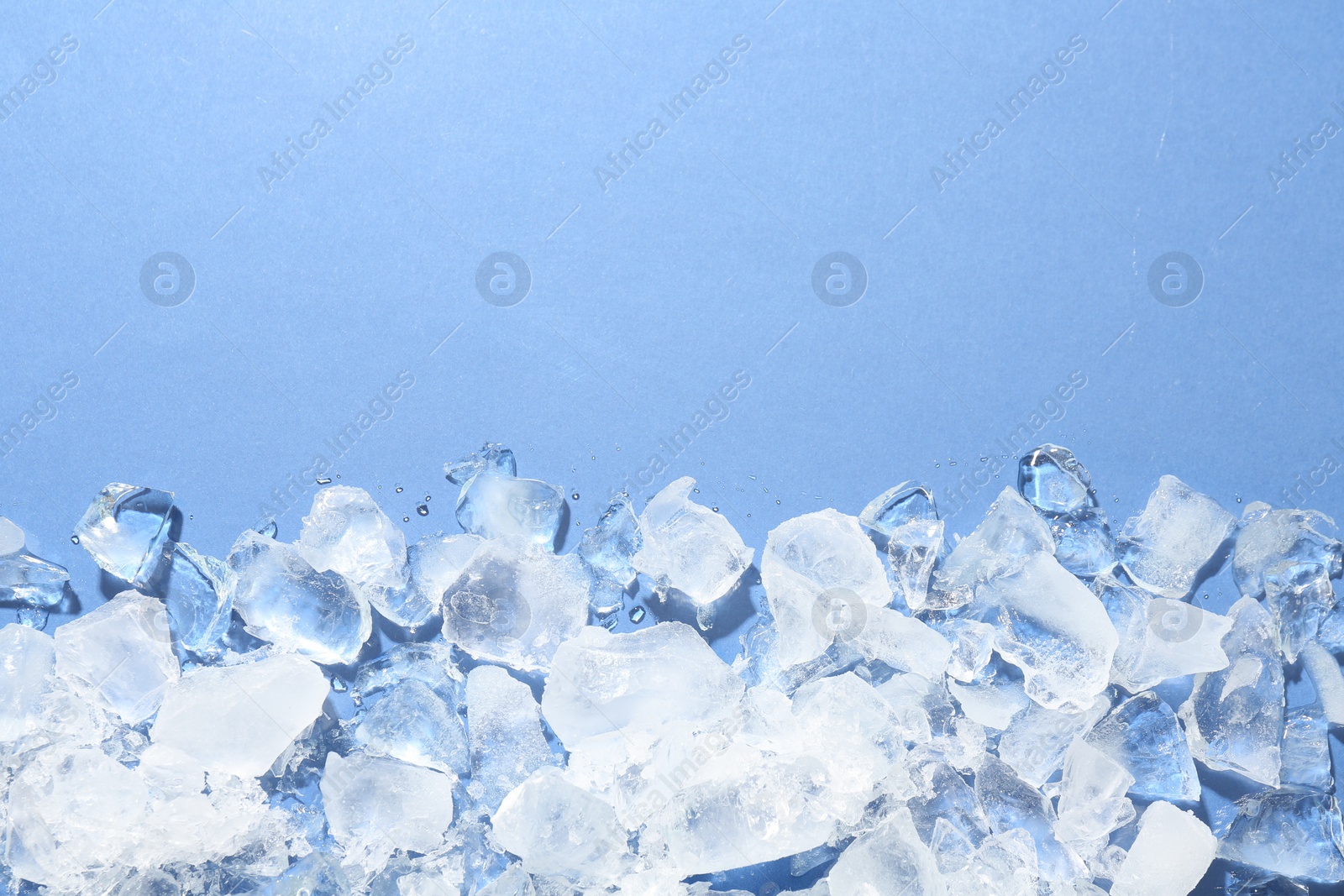 Photo of Pieces of crushed ice on light blue background, flat lay. Space for text