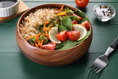 Photo of Tasty fried rice with vegetables served on green wooden table, closeup