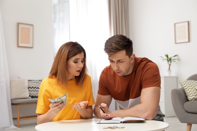 Sad couple counting money in living room