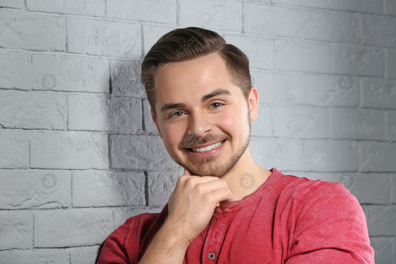 Photo of Portrait of young man with beautiful hair on brick wall background