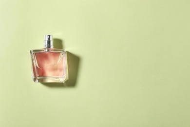 Bottle of perfume on color background, top view