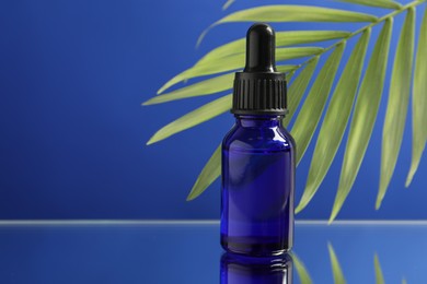 Bottle of face serum on blue background, closeup. Space for text