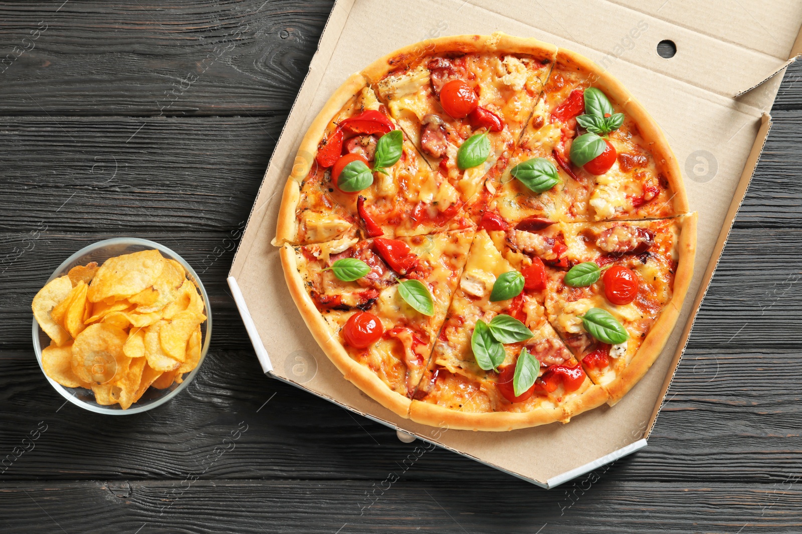 Photo of Delicious pizza with tomatoes and sausages in cardboard box on table, top view