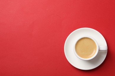 Photo of Aromatic coffee in cup on red background, top view. Space for text