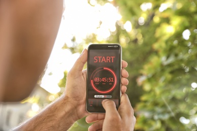 Photo of Man using fitness app on smartphone outdoors, closeup