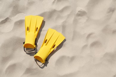 Photo of Pair of yellow flippers on sand, top view. Space for text