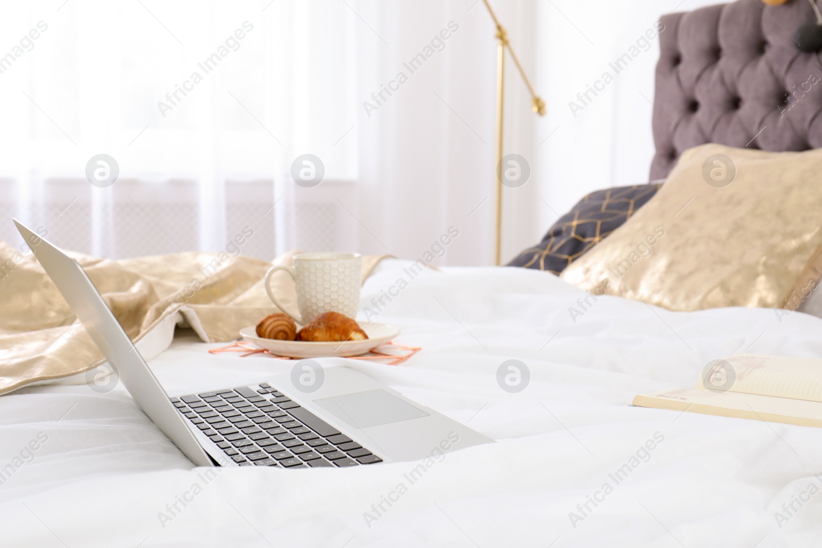 Photo of Laptop and breakfast on bed in stylish room interior