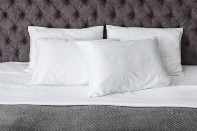 Soft white pillows on comfortable bed, closeup