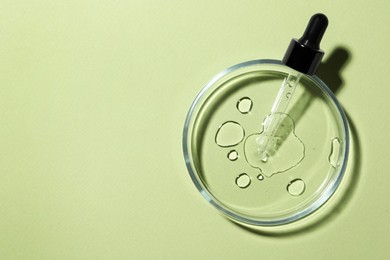 Petri dish with sample and pipette on light green background, top view. Space for text