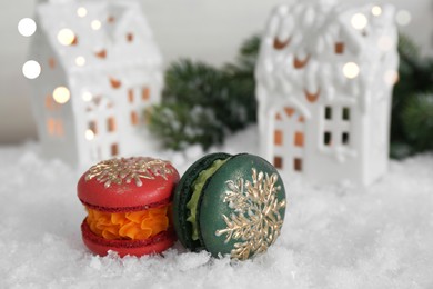 Different decorated Christmas macarons on table with artificial snow, closeup