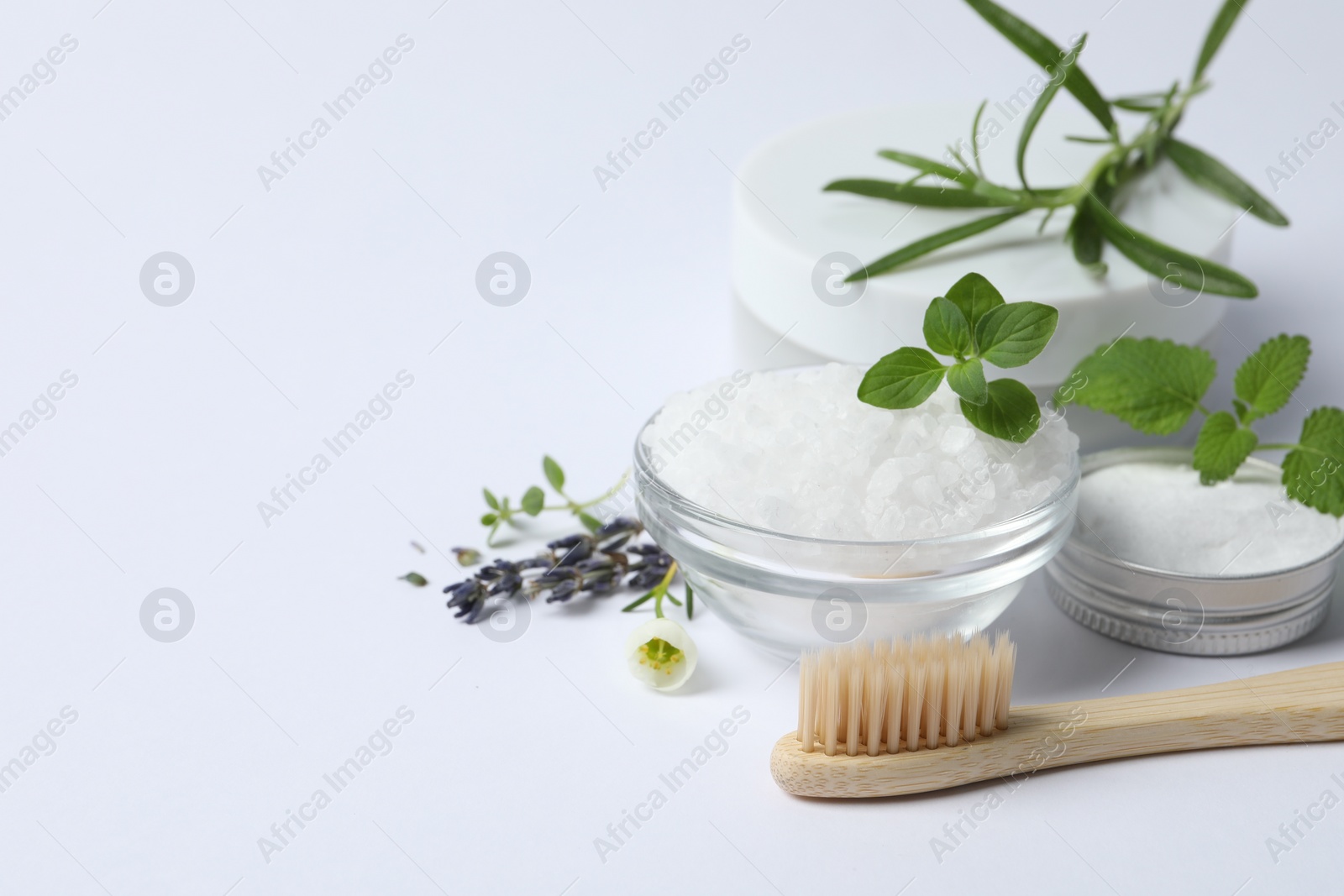 Photo of Toothbrush, sea salt, dry flowers and green herbs on white background, closeup. Space for text