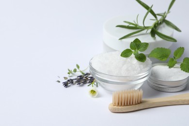 Toothbrush, sea salt, dry flowers and green herbs on white background, closeup. Space for text