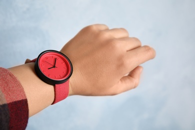 Woman with stylish wrist watch on color background, closeup. Time management