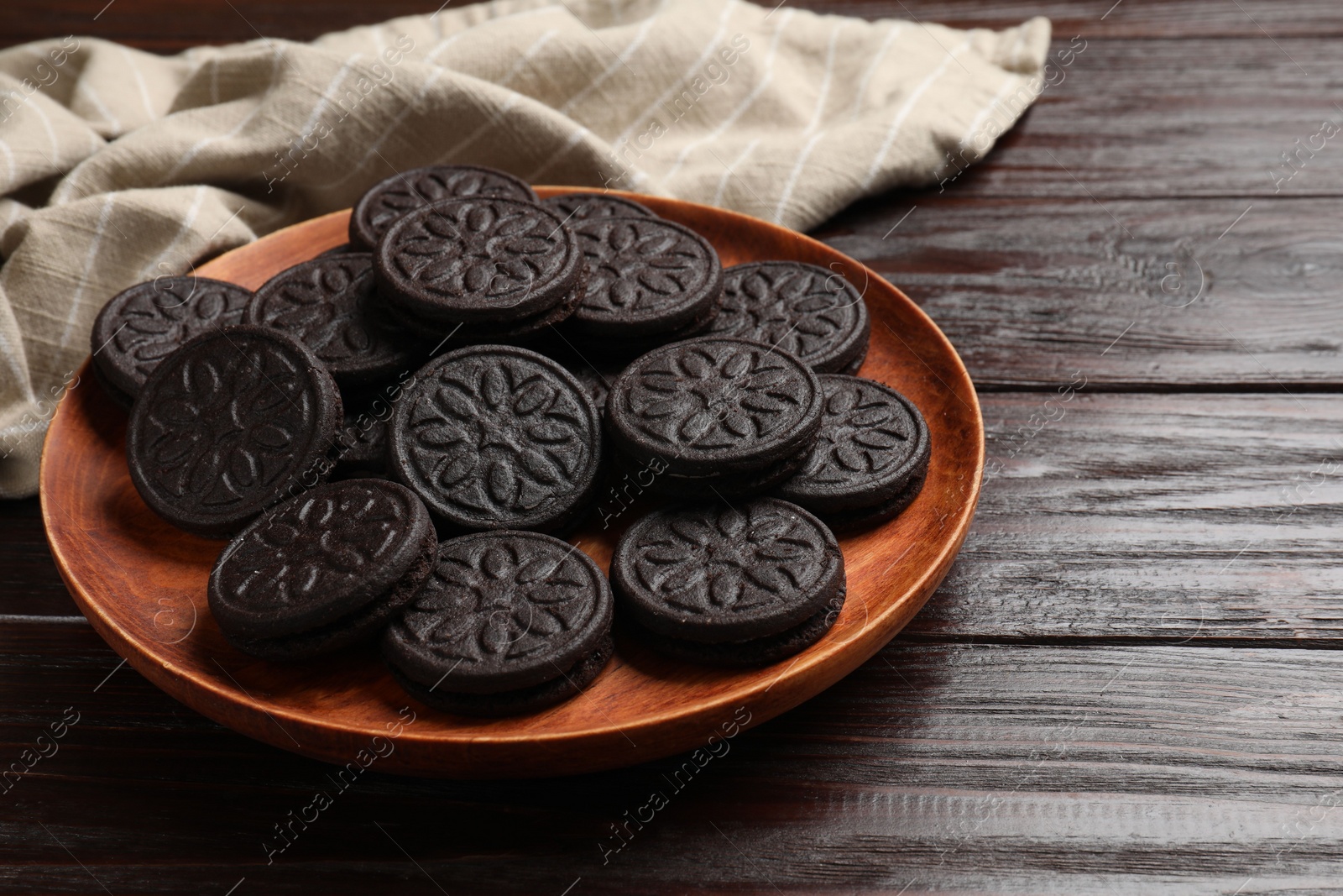 Photo of Plate with tasty sandwich cookies on wooden table, closeup