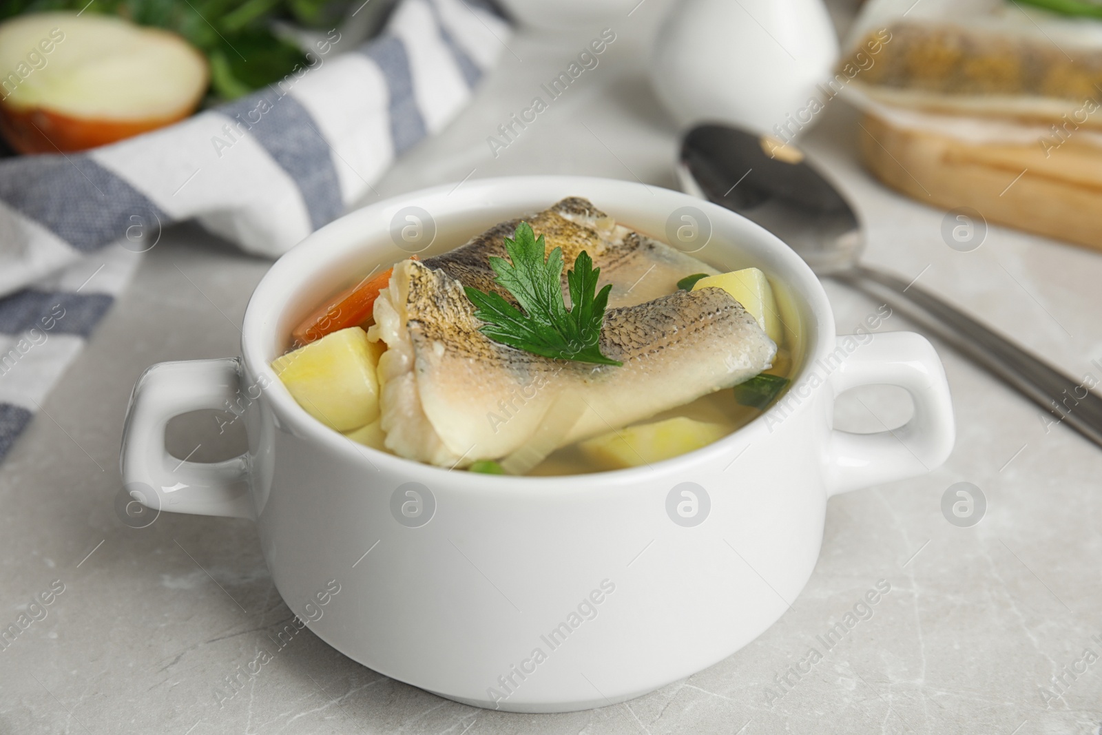 Photo of Delicious fish soup in bowl on light table, closeup