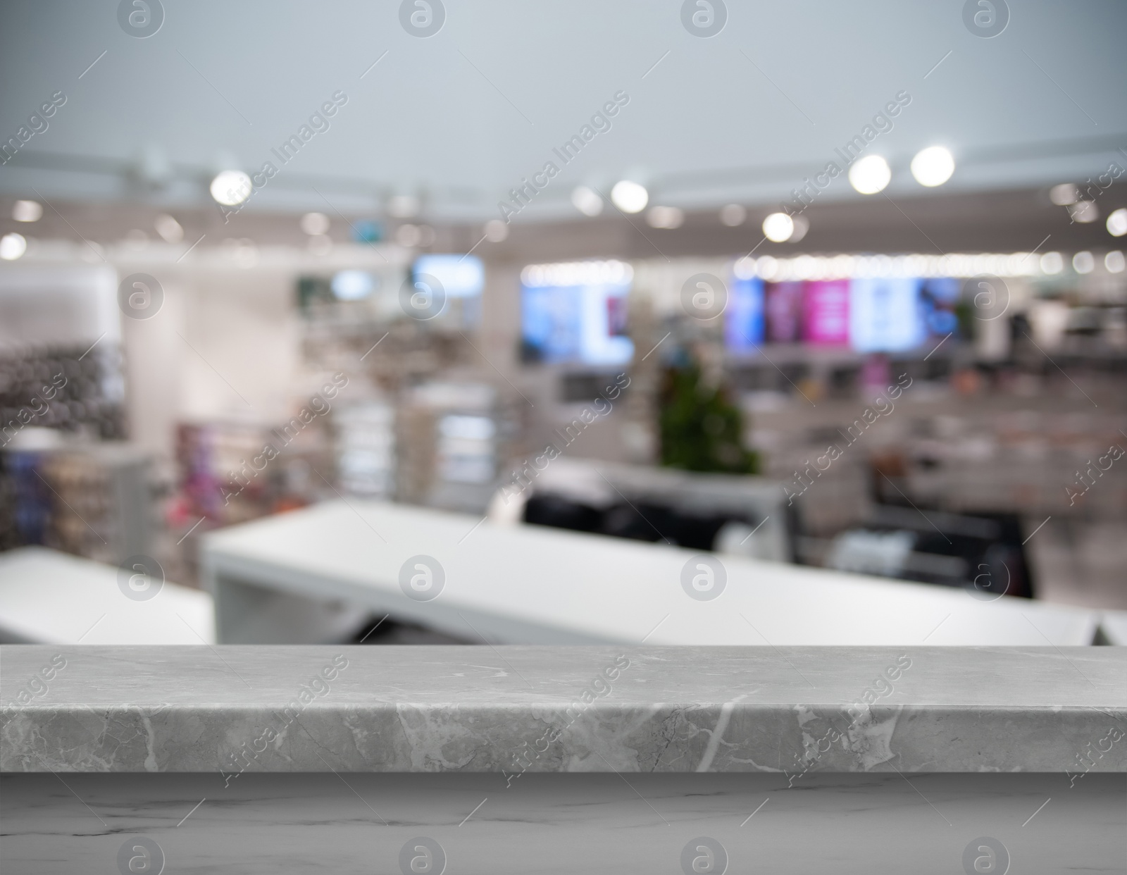 Image of Empty light grey marble surface and blurred view of clothes store interior. Space for design