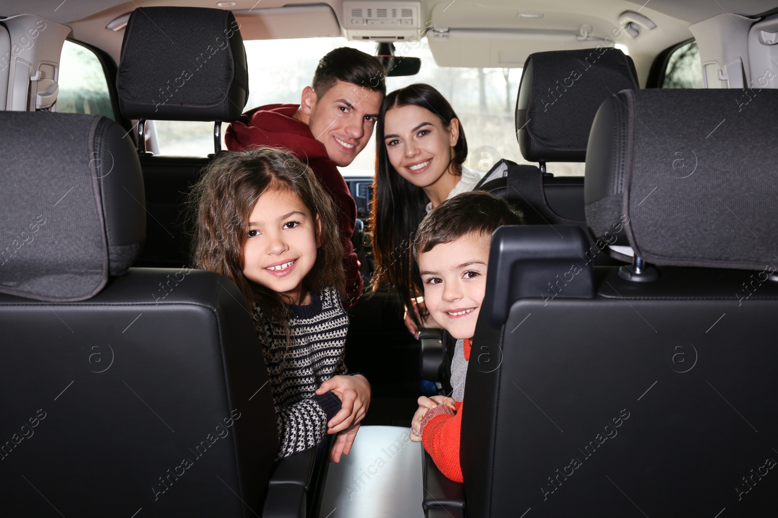 Photo of Happy family with little children inside modern car