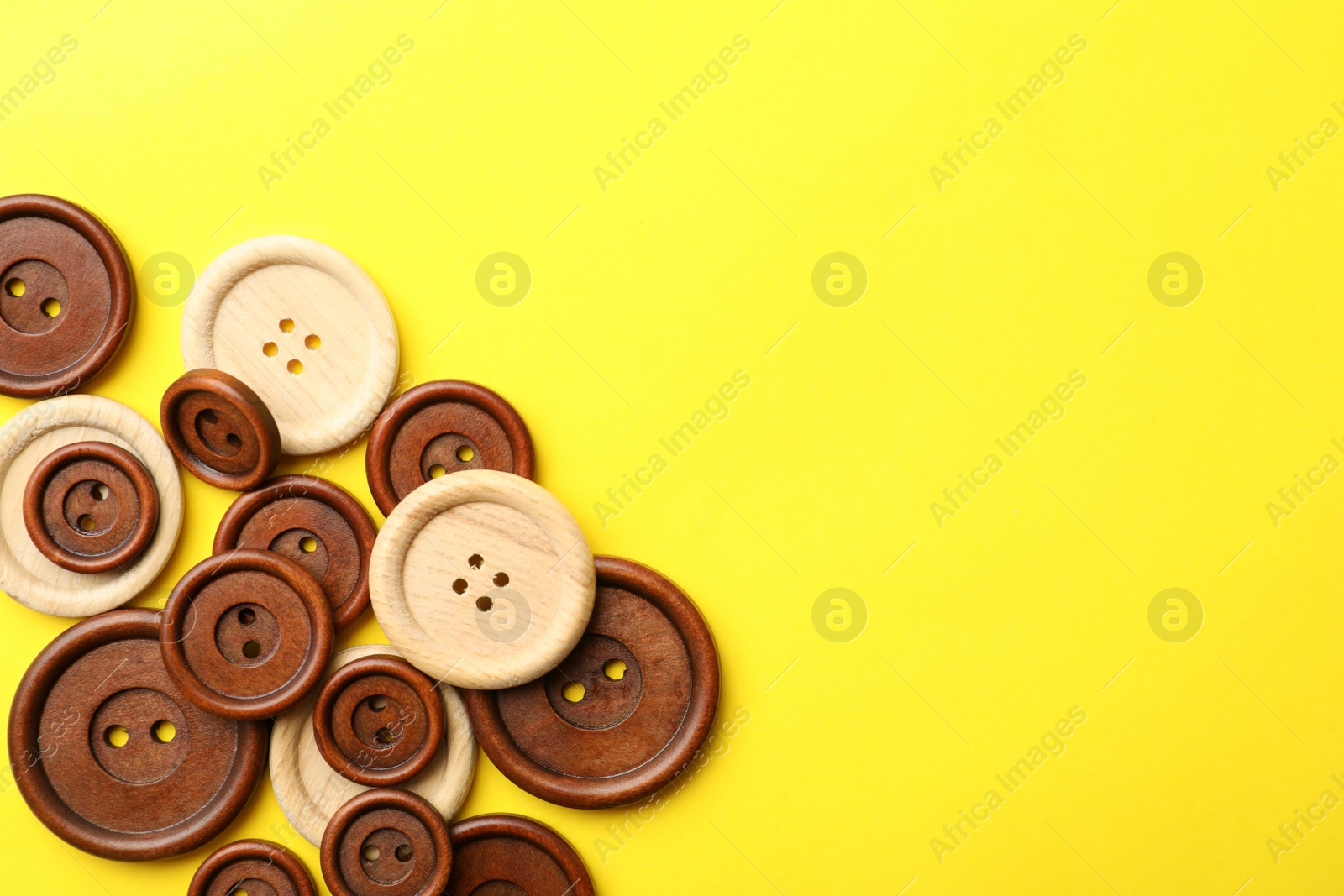 Photo of Many colorful sewing buttons on yellow background, flat lay. Space for text