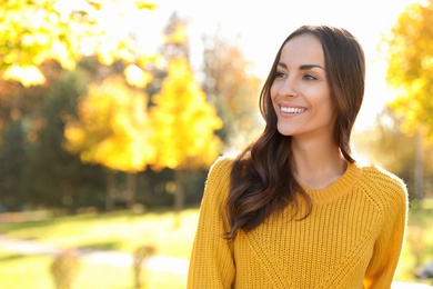 Photo of Beautiful woman wearing yellow sweater in park. Autumn walk