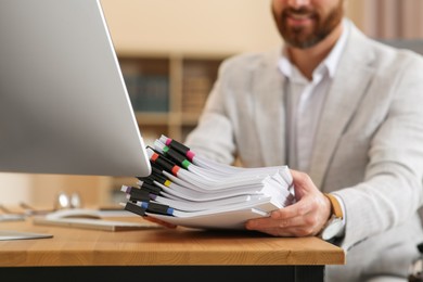 Businessman with documents at wooden table in office, closeup