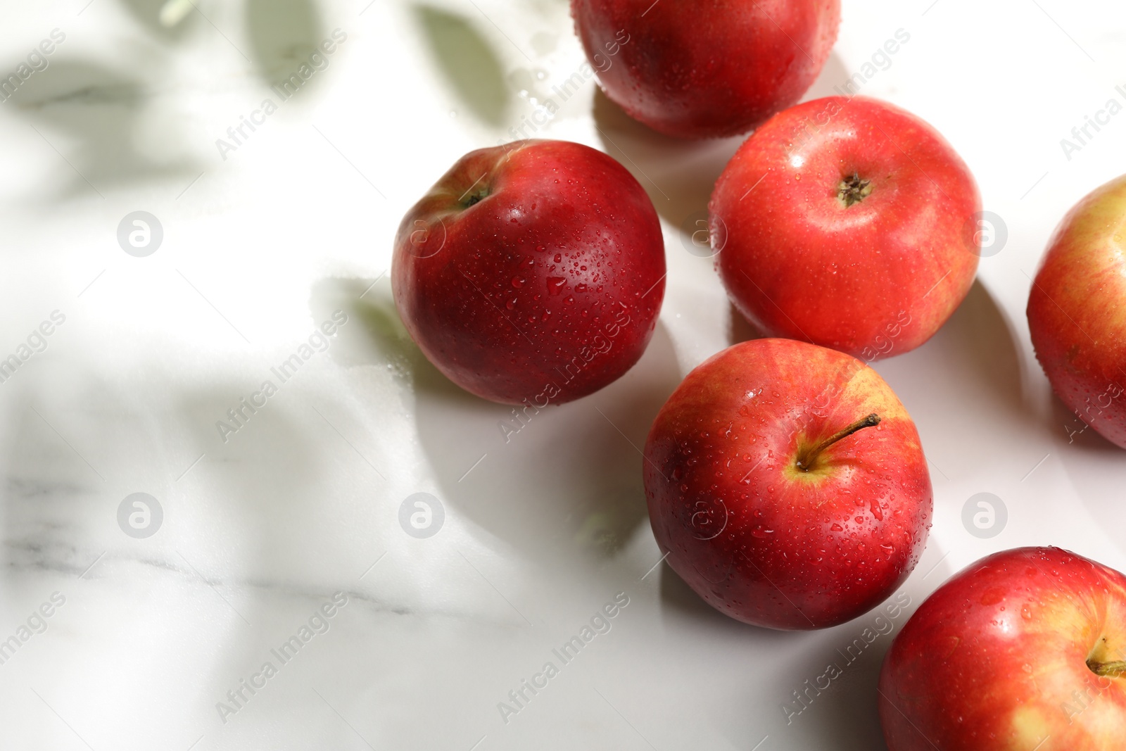 Photo of Fresh red apples with water drops on white marble table, flat lay. Space for text