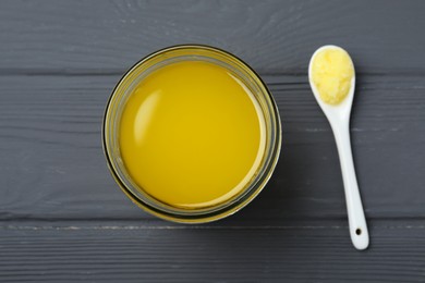 Glass jar and spoon of Ghee butter on grey wooden table, flat lay