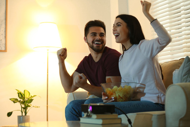 Photo of Happy young couple watching TV using video projector at home