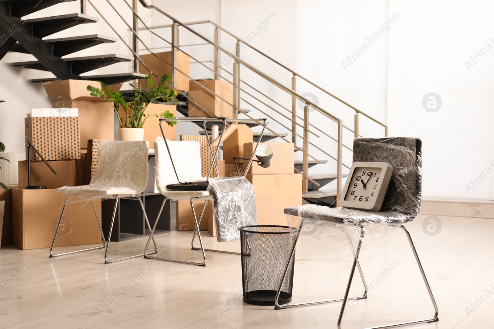 Photo of Cardboard boxes with packed stuff near stairs in office. Moving day