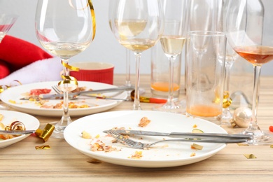 Photo of Dirty dishes with leftovers on wooden table after party