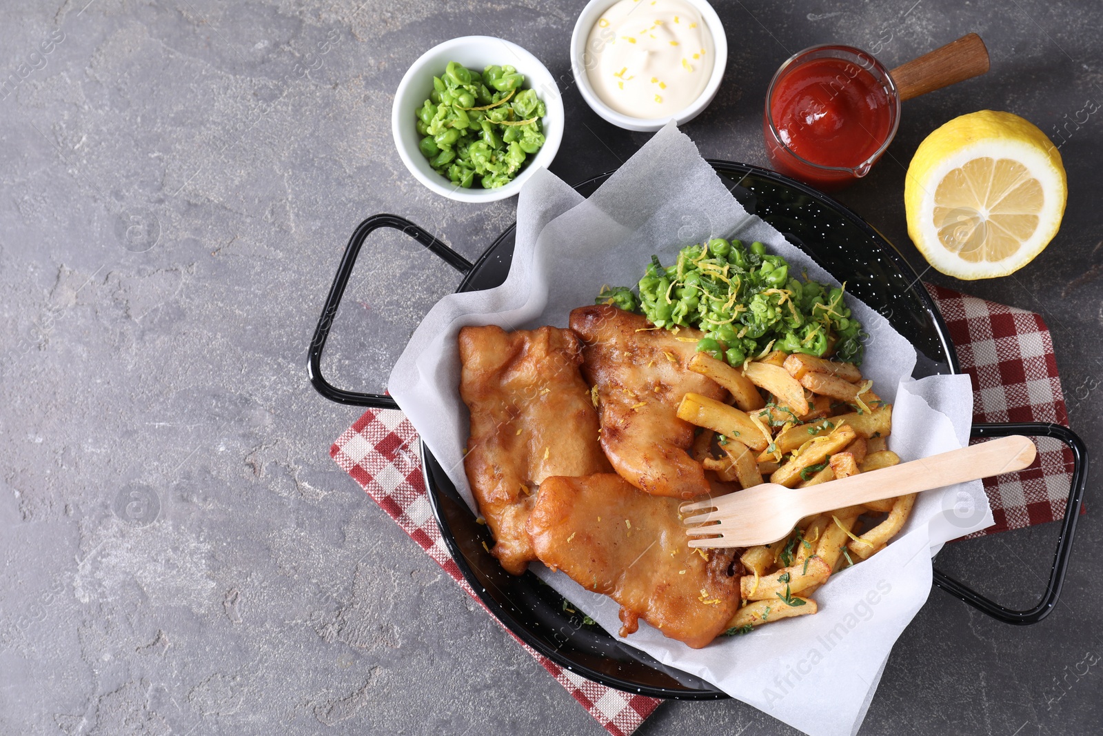 Photo of Tasty fish, chips, sauces and peas on grey table, flat lay. Space for text