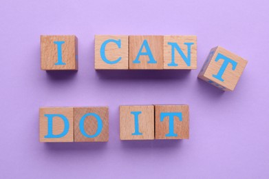 Photo of Motivation concept. Changing phrase from I Can't Do It into I Can Do It by removing wooden cube with letter T on violet background, top view