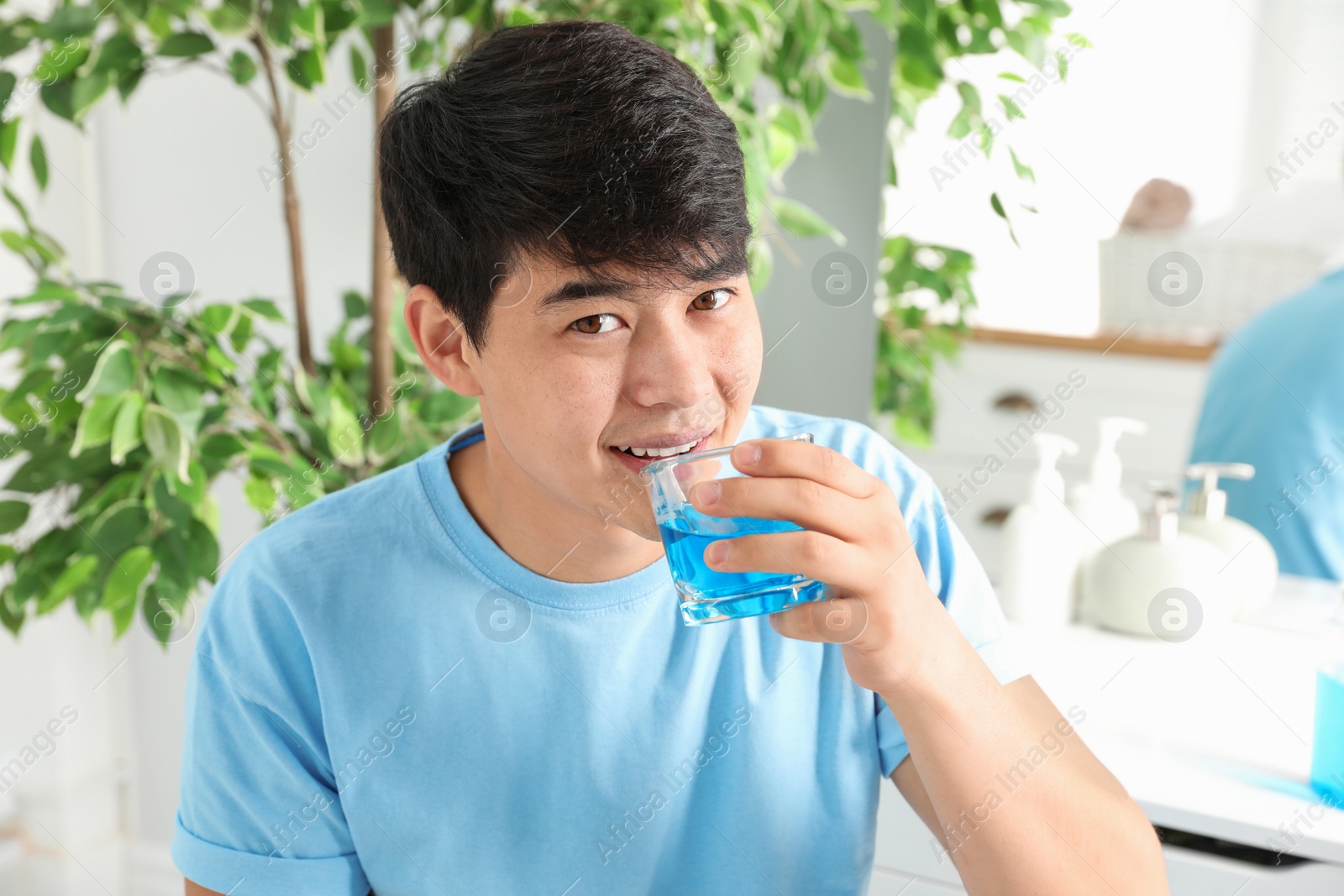 Photo of Man rinsing mouth with mouthwash in bathroom. Teeth care