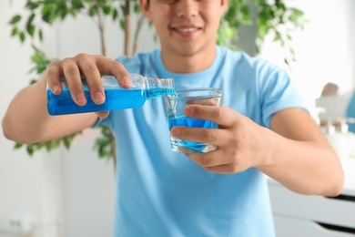 Man pouring mouthwash from bottle into glass, closeup. Teeth care