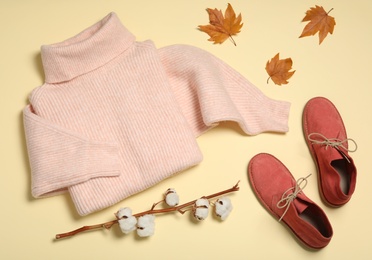 Photo of Flat lay composition with sweater and dry leaves on yellow background. Autumn season