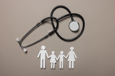 Photo of Paper family figures and stethoscope on light grey background, flat lay. Insurance concept