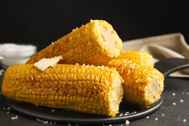 Photo of Delicious grilled corn with butter on table, closeup