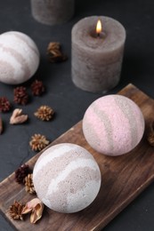 Photo of Bath bombs, dry flowers and burning candle on black table