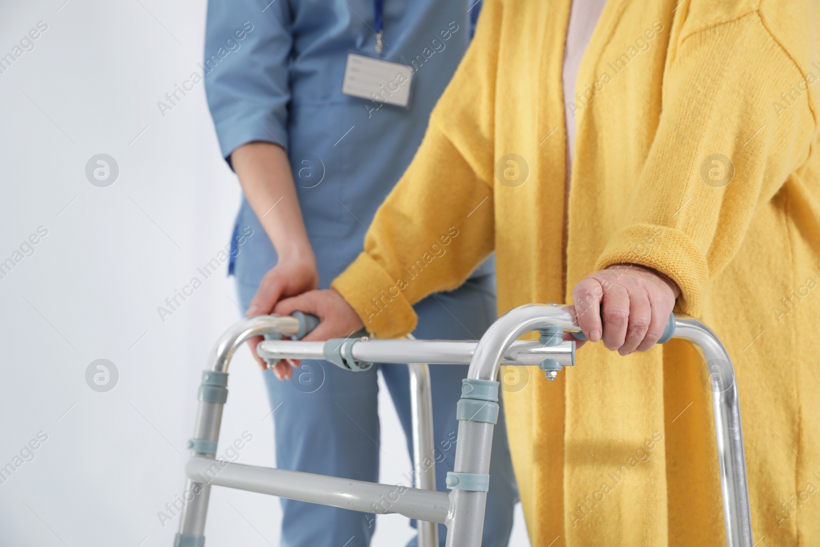 Photo of Nurse assisting senior woman with walker in hospital, closeup