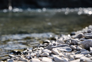 Photo of River coast with stones and pebbles on sunny day