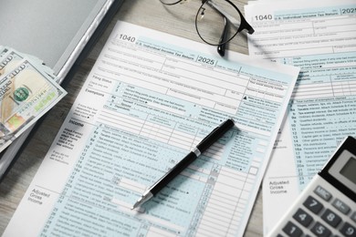 Payroll. Tax return forms, pen, glasses and dollar banknotes on wooden table, above view