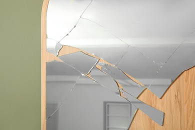 Photo of Broken mirror with many cracks near olive wall, closeup view