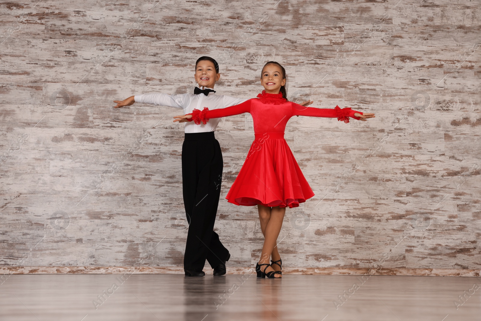 Photo of Beautifully dressed couple of kids dancing together in studio