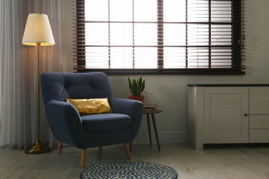 Photo of Stylish living room interior with comfortable armchair and window blinds