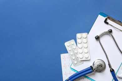 Flat lay composition with medical equipment and pills on blue background. Space for text