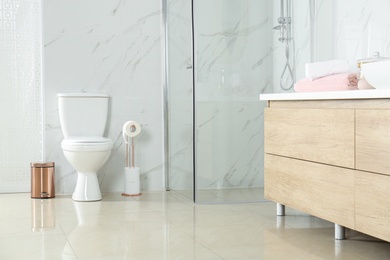 Photo of Toilet bowl near shower stall in modern bathroom interior